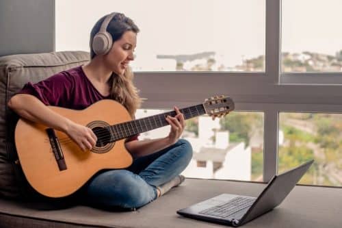Woman learning how to play guitar on online class